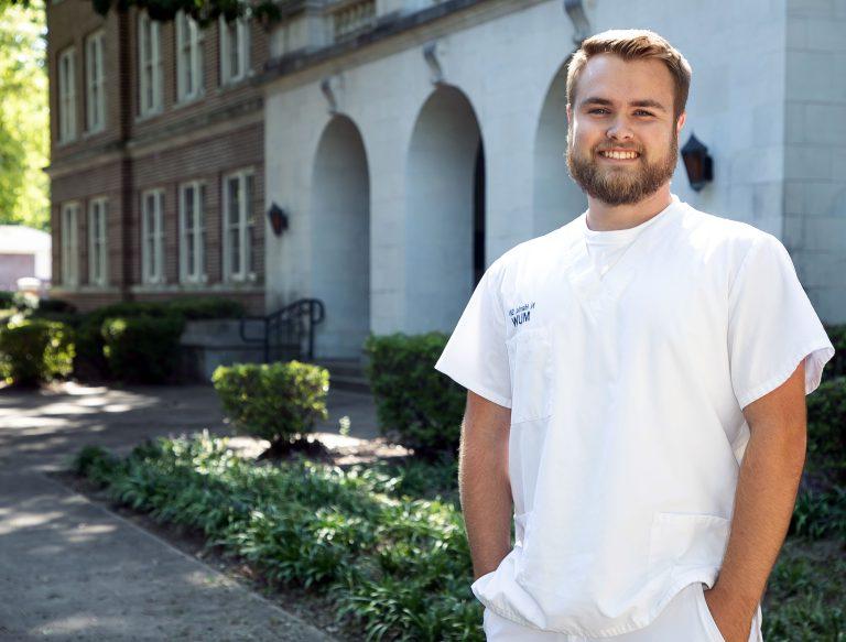 Male nursing student stands in front of Martin Hall